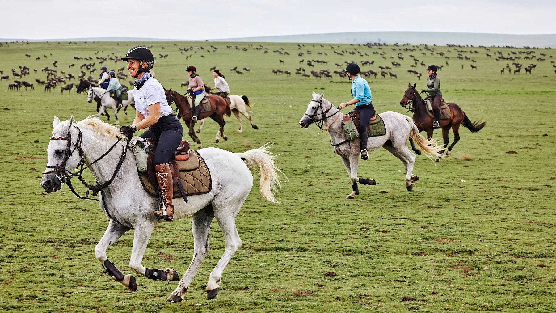 Experienced riders cantering together across open grassland