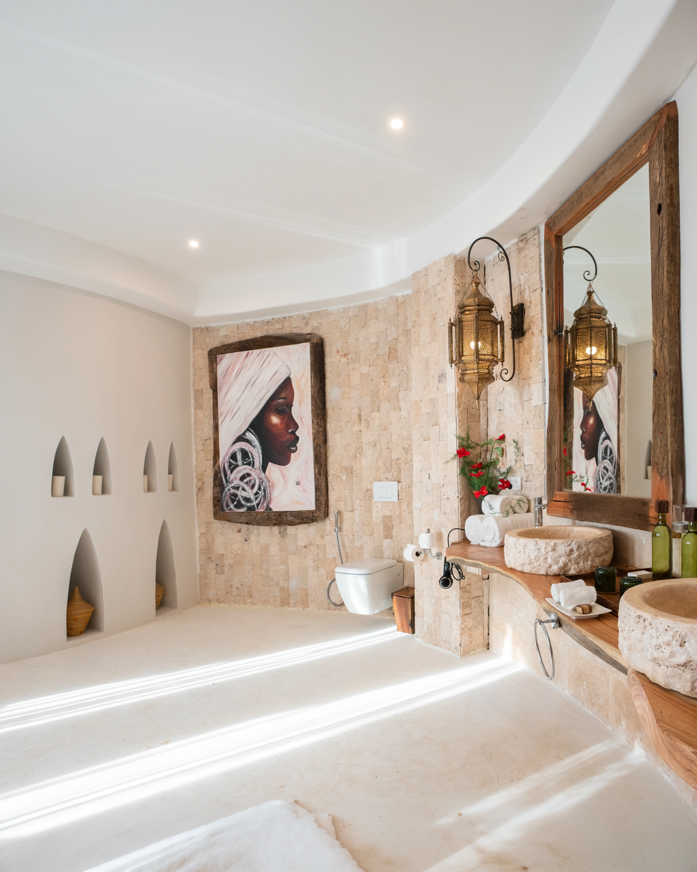 Bright Zanzibar bathroom with a framed portrait and carved mirror